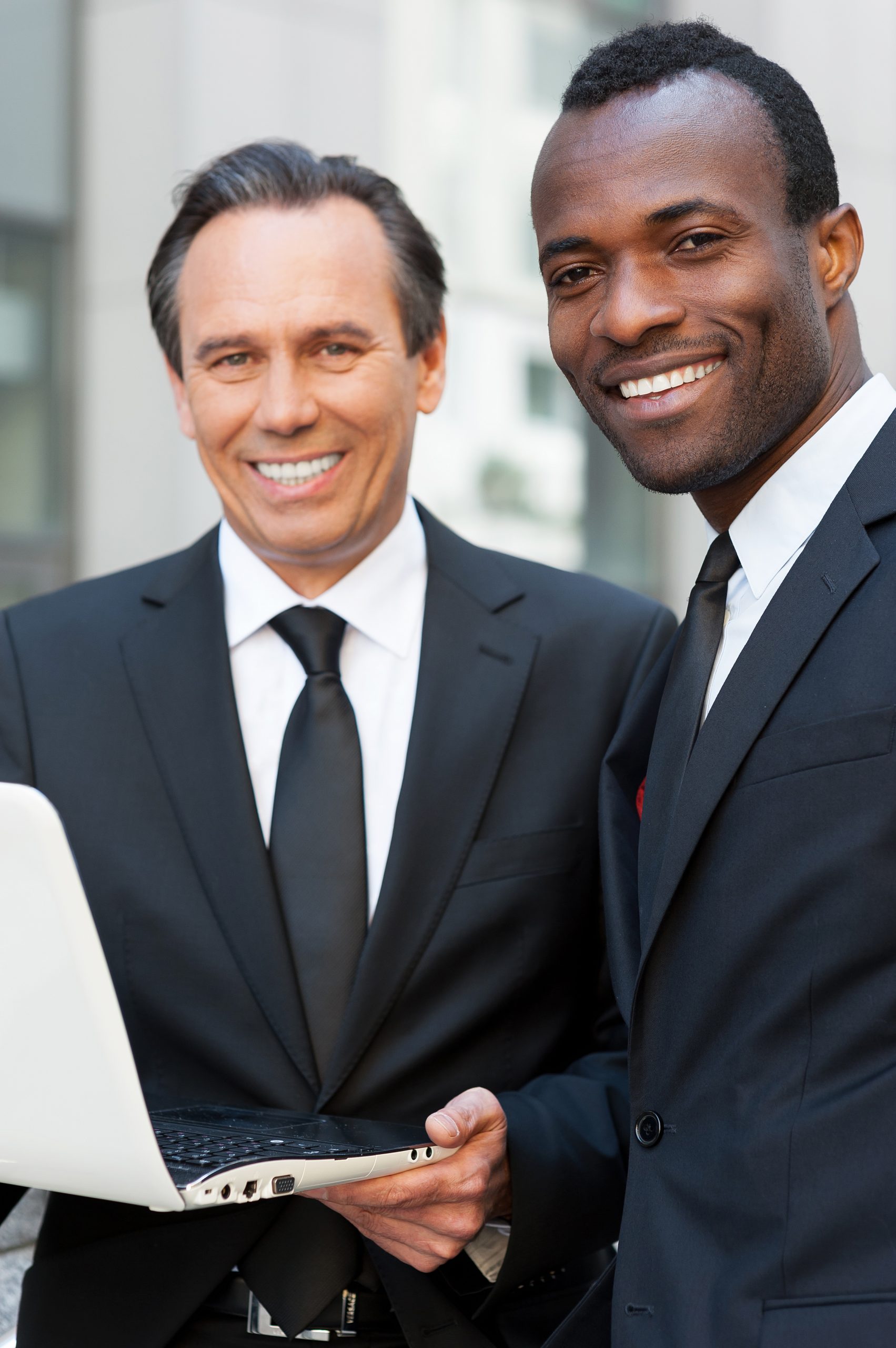 Business discussion. Two confident business men looking at laptop while one of them pointing it with finger