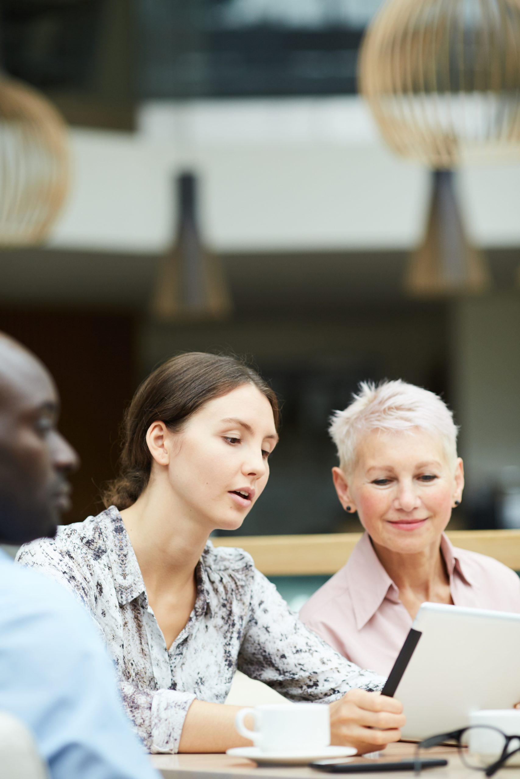 Portrait of young businesswoman using digital tablet during meeting with group of colleagues, copy space