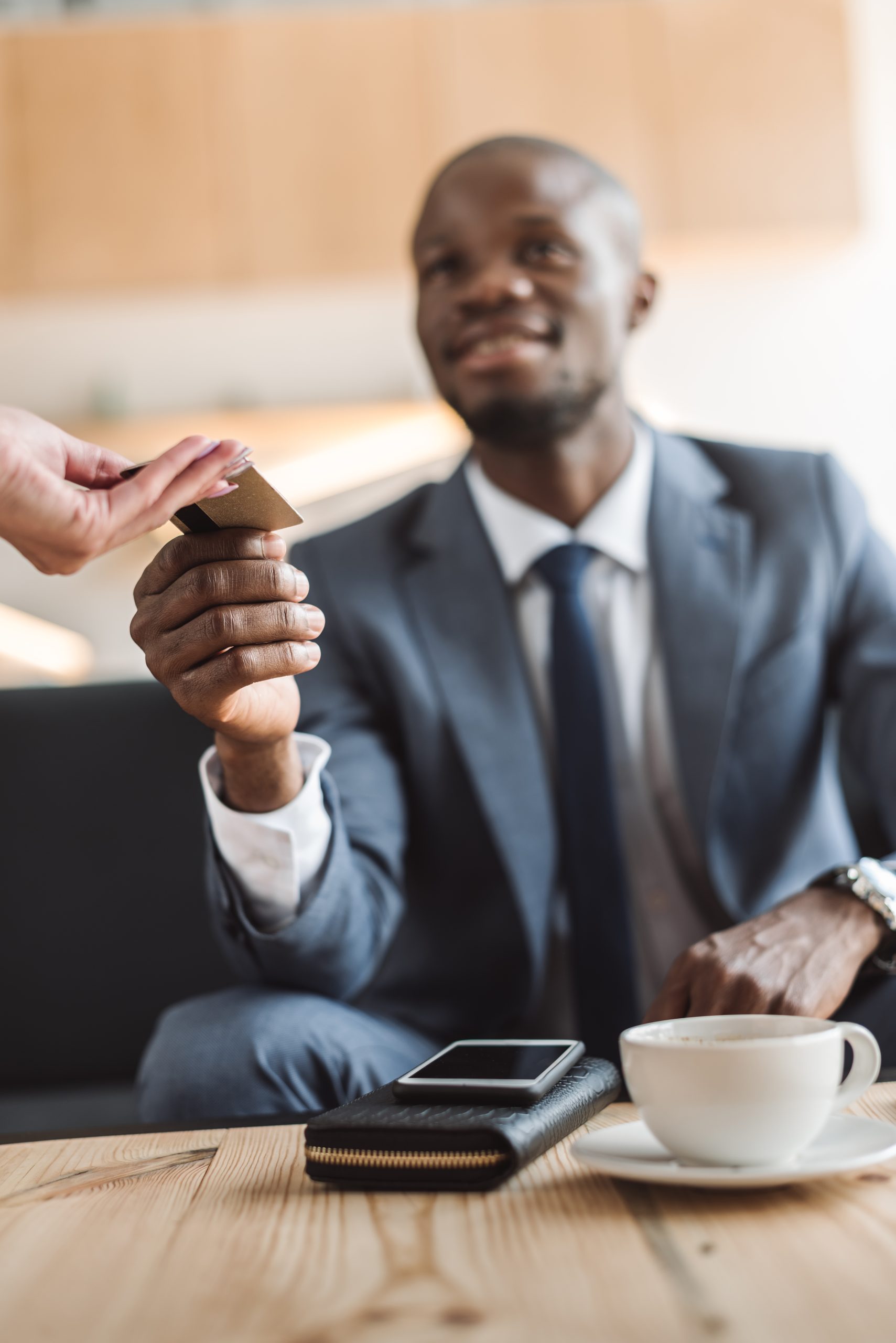 handsome smiling african american businessman paying with credit card in cafe